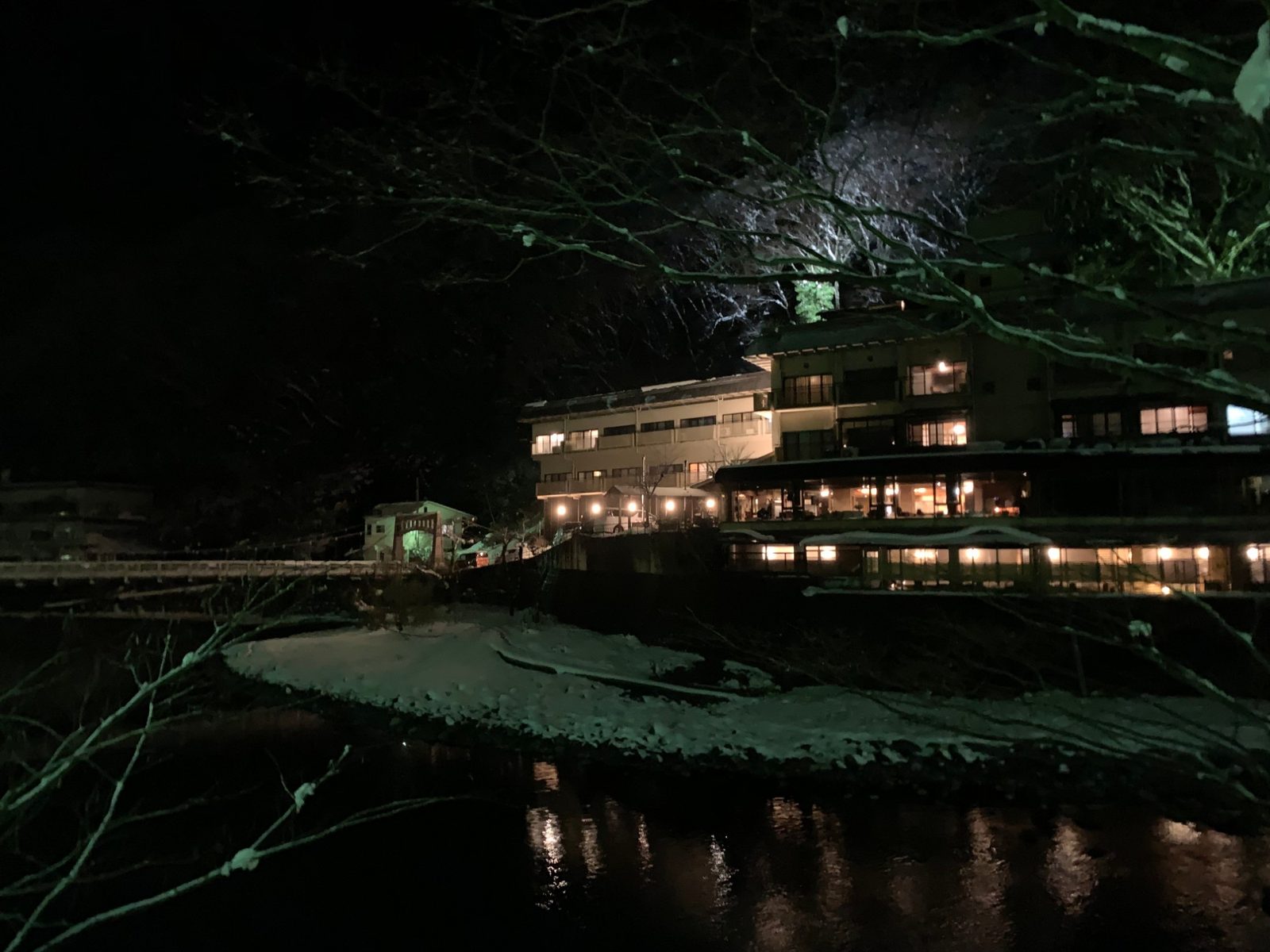 雪の夜、川沿いに灯りをともす湯原温泉の宿